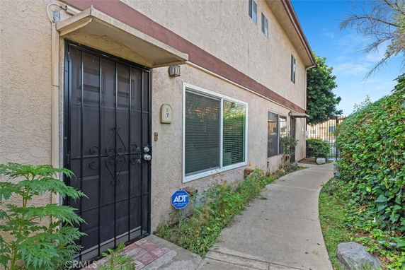 Front view of a two-story building with a security screen door and windows.