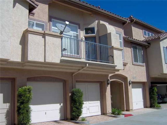Front view of a multi-story house with a balcony and garage doors.