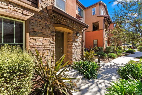 Front view of a multi-story house with stone facade and landscaped walkway.