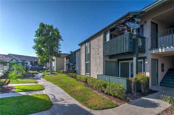 Front view of a two-story apartment building with balconies and a walkway.
