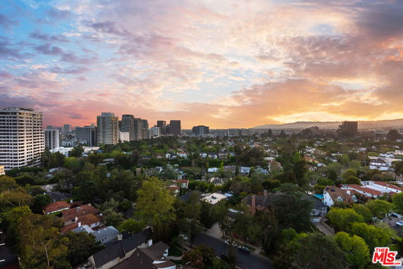 Panoramic view of a cityscape at sunset featuring residential areas and high-rise buildings.