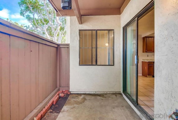 View of a small patio area with a sliding glass door and wooden fence.