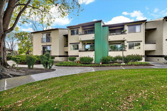 Front view of a multi-story residential building with balconies and a green facade accent.