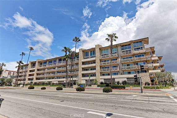 Front view of a multi-story building with balconies and palm trees.
