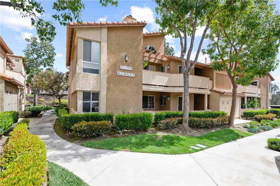 Front view of a two-story residential building with balconies and beige exterior walls.