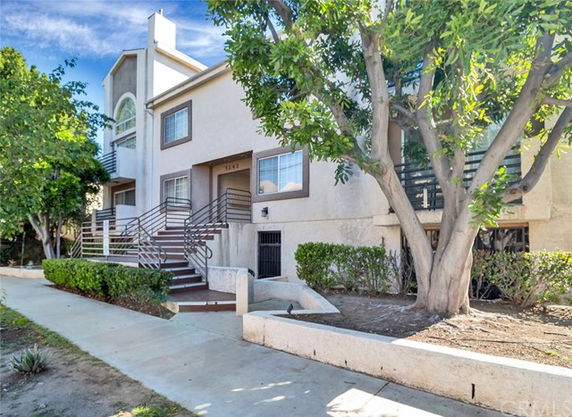 Front view of a two-story residential building with a staircase leading to the entrance.