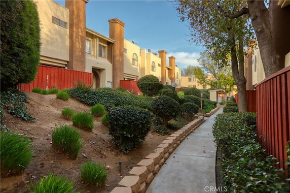 Front view of a multi-story apartment building with a walkway and landscaped areas.