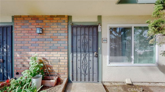 Front view of a house entrance with a metal security door and a brick wall.