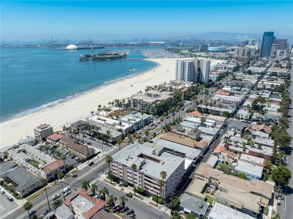Aerial panoramic view of beachfront buildings with a wide stretch of beach and ocean in the background.