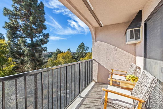 Balcony with chairs overlooking trees and distant landscape.
