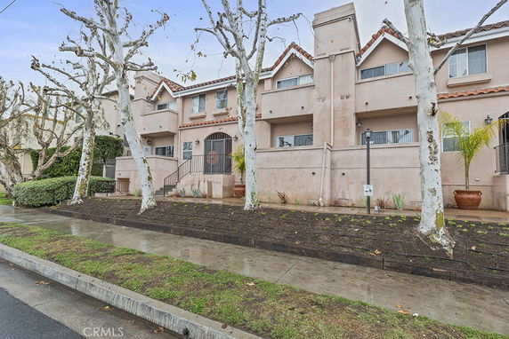 Front view of a two-story residential building with a staircase leading to the entrance.