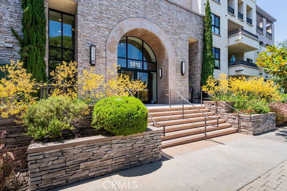 Front view of a multi-story building with a stone facade and an arched entrance.
