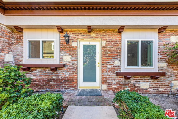 Front view of a brick house with two windows and a glass door.