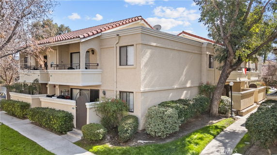 Front view of a two-story apartment building with balconies and a tiled roof.