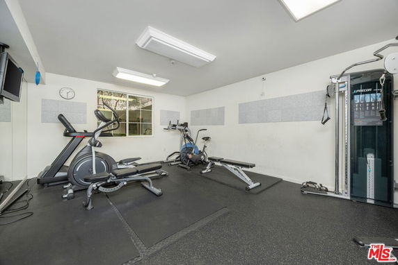 Indoor gym area with exercise equipment and a wall-mounted television.