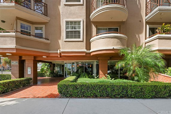 Front view of a multi-story building with balconies and landscaped entrance.
