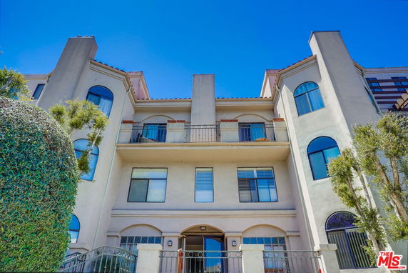 Front view of a multi-story building with arched windows and balconies.