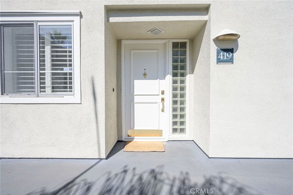 Front view of a house with a white door and window with shutters.