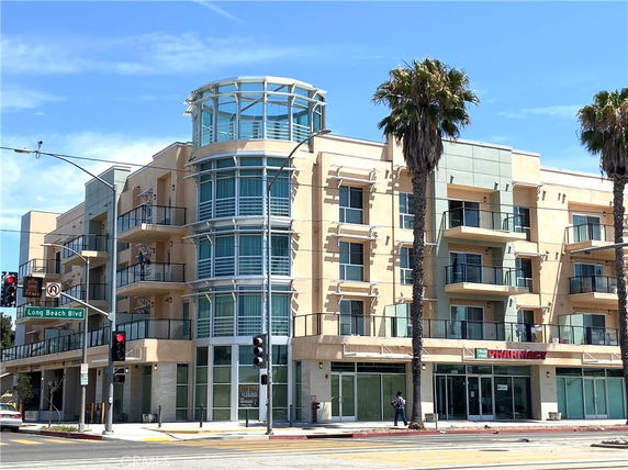 Front view of a multi-story commercial and residential building with balconies and large windows.