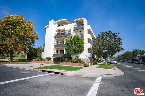 Front view of a multi-story apartment building on a street corner.