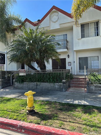Front view of a two-story house with a balcony and lawn.