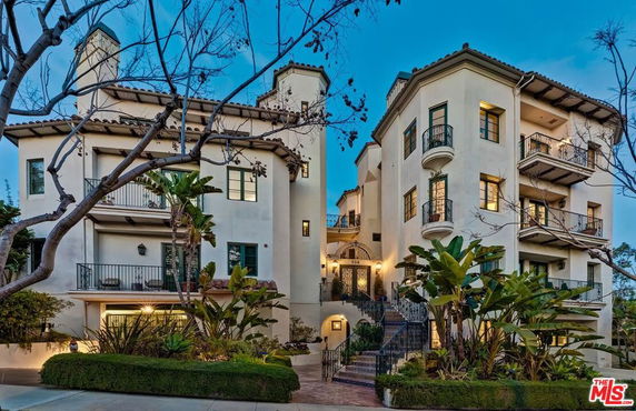 Front view of a multi-story residential building with multiple balconies and a central entrance.
