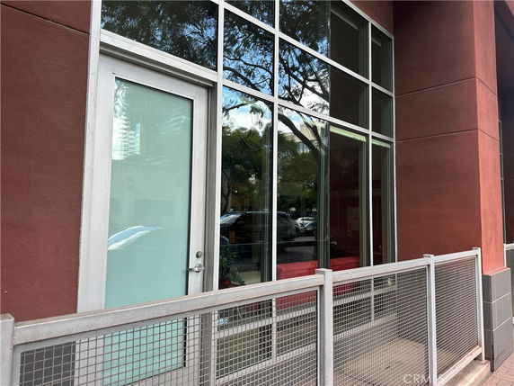 Front view of a building with large windows and a door, featuring a metal railing.
