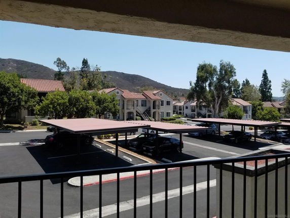 Outdoor parking area with covered parking spaces and view of residential buildings.
