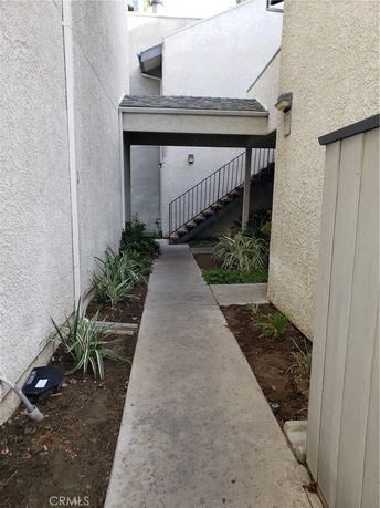Outdoor pathway with stairs leading to an elevated entrance in a residential area.