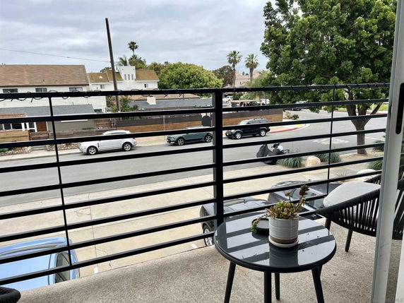 View from a balcony overlooking a street with parked cars and houses.