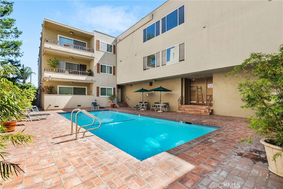 Outdoor swimming pool area adjacent to a multi-story residential building.