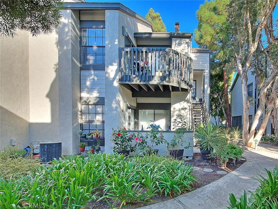 Front view of a two-story residential building with a balcony and garden area.