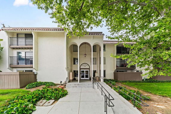 Front view of a two-story building with arched entryway and balconies.