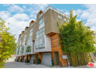Front view of a modern multi-story building with large windows and wooden accents.