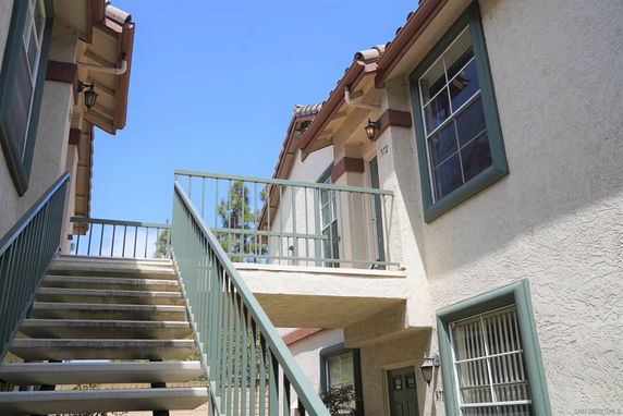 Exterior view of a multi-story building with a staircase leading to a second-floor entrance.