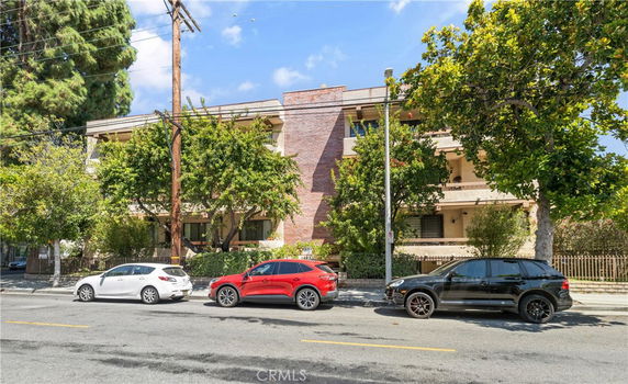 Front view of a multi-story building with a brick facade and balconies.