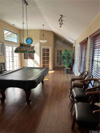 Interior view of a room with a pool table, chairs, and large windows.