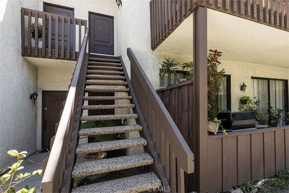 Front view of an apartment building with exterior stairs leading to the upper level.