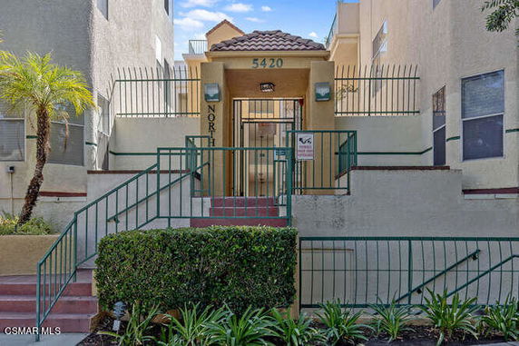 Front view of a multi-story building entrance with stairs and metal railings.
