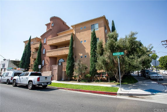 Front view of a multi-story building with balconies and a rounded corner feature.