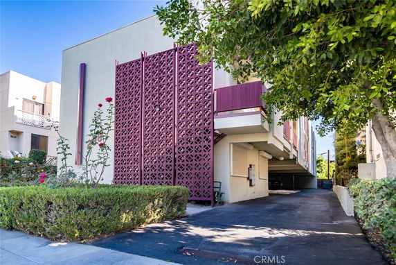 Front view of a building with a decorative lattice screen and parking space underneath.