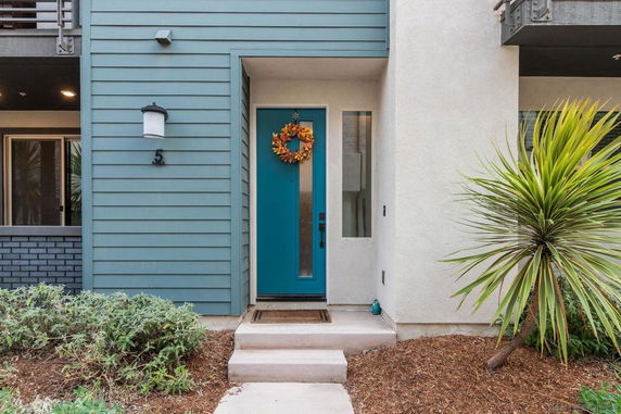 Front view of a house entrance with a teal door and decorative wreath.