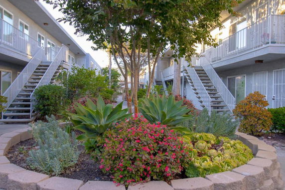 Front view of a two-story building with exterior staircases and landscaped garden.