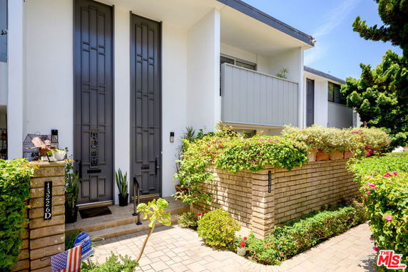 Front view of a modern two-story house with a balcony and large double doors.