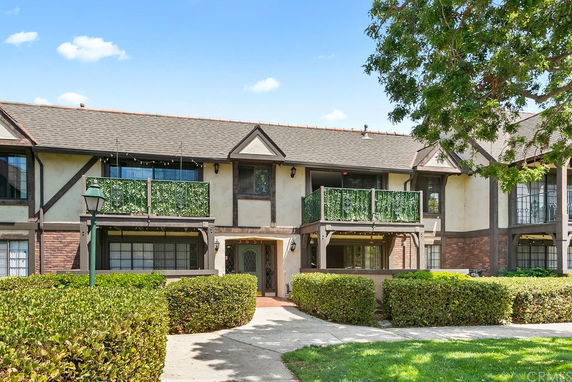 Front view of a two-story house with balconies and decorative green railings.
