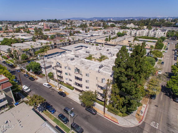 Aerial view of a residential building in an urban area with other buildings and streets surrounding it.