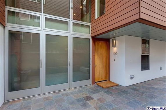 Front view of a modern house entrance with large glass doors and a wooden door.