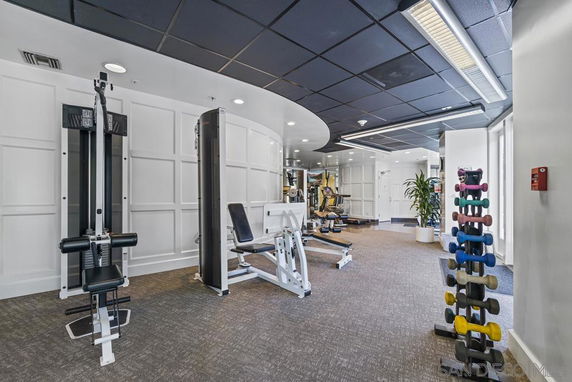 Interior view of a gym with exercise equipment and dumbbells.