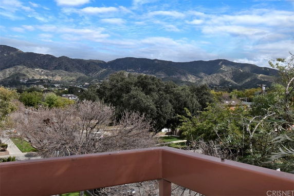 Panoramic view of mountains and trees from a balcony.
