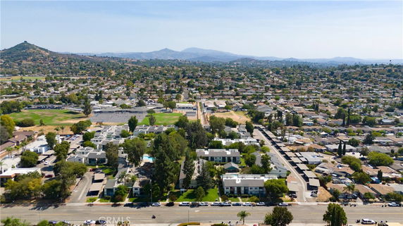 Aerial view of a residential area with houses and buildings spread across a landscape with hills in the background.